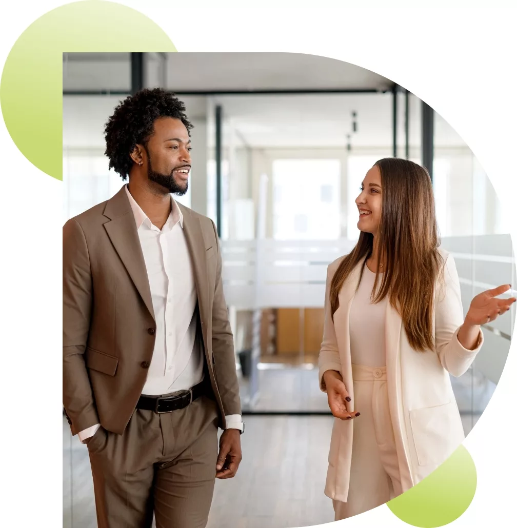 two business professionals talking in a brightly lit office hallway